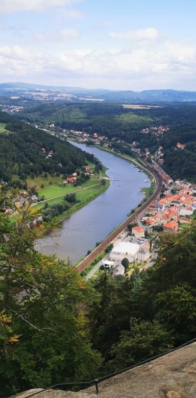 Blick von oben auf einen Fluss, umgeben von grünen Hügeln und einer Stadt.